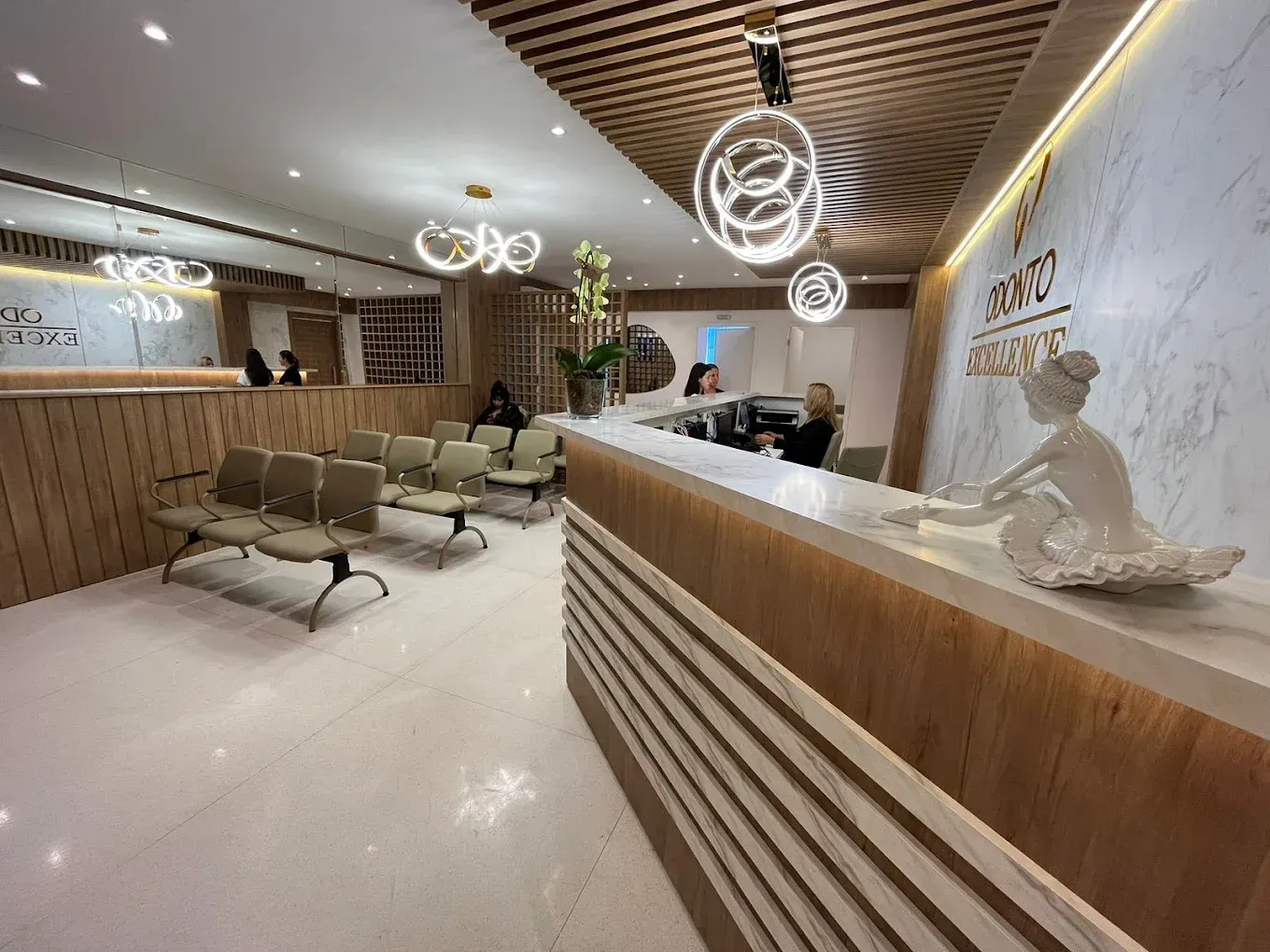 Recepção da clínica Odonto Excellence, com balcão em mármore e madeira e área de espera.